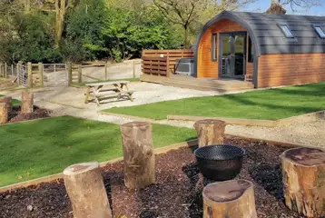 The Den glamping pod exterior with private hot tub, outdoor seating and fire pit The Den glamping pod exterior with private hot tub, outdoor seating and fire pit