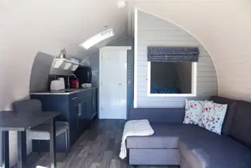 The Nest glamping pod interior with bed, kitchenette, living and dining areas The Nest glamping pod interior with bed, kitchenette, living and dining areas