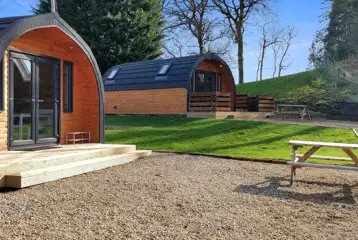 The Den and Roost glamping pod exteriors and decking, with outdoor seating The Den and Roost glamping pod exteriors and decking, with outdoor seating