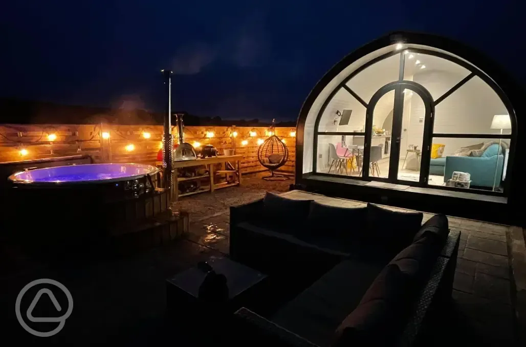 White Clover pod at night with lights and a private wood-fired hot tub White Clover pod at night with lights and a private wood-fired hot tub