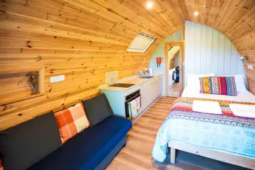 Chimpanzee large ensuite glamping pod interior with double bed and living area Chimpanzee large ensuite glamping pod interior with double bed and living area