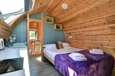Glamping pod interior with a king size bed, bedding, towels and ensuite