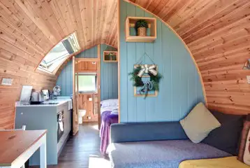 Glamping pod interior with an L-shaped sofa bed and half dividing wall Glamping pod interior with an L-shaped sofa bed and half dividing wall
