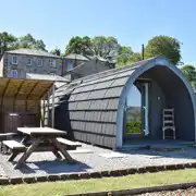 Glamping pod with a covered wood-fired hot tub and picnic bench