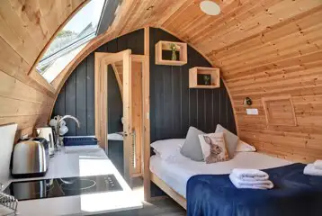 King size bed with bedding and towels alongside the kitchenette King size bed with bedding and towels alongside the kitchenette