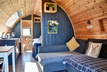 Glamping pod interior with an L-shaped sofa bed and half dividing wall Glamping pod interior with an L-shaped sofa bed and half dividing wall