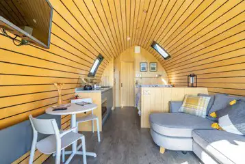 Glamping pod interior with dining space and TV Glamping pod interior with dining space and TV