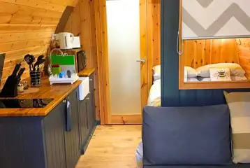 Pod interior with lounge area, bed, kitchenette and door to the ensuite bathroom Pod interior with lounge area, bed, kitchenette and door to the ensuite bathroom