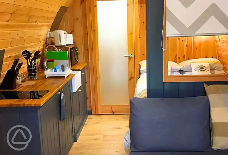 Pod interior with lounge area, bed, kitchenette and door to the ensuite bathroom