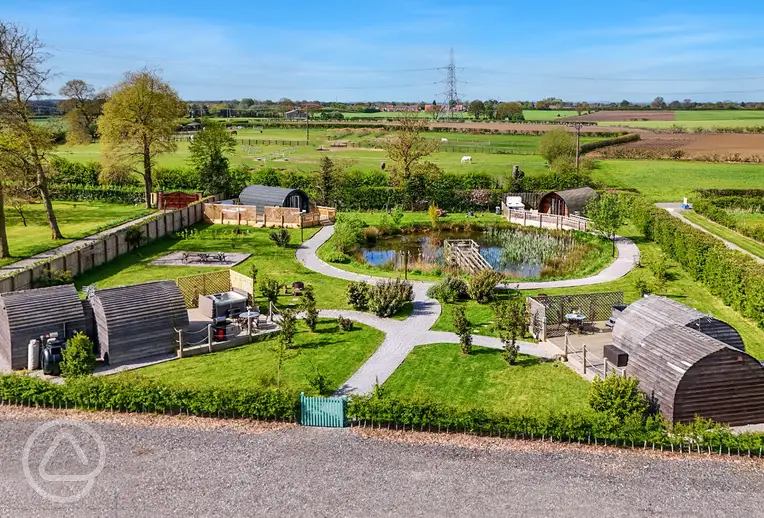 Four glamping pods set around a wildlife pond