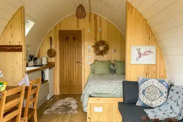 Bowcliffe pod interior with a double bed, bedding, kitchen and sofa bed Bowcliffe pod interior with a double bed, bedding, kitchen and sofa bed