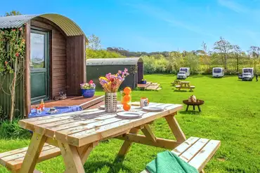 Camping pods with outdoor seating and views towards the electric grass pitches