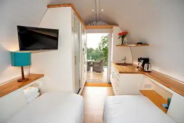 Standard ensuite pod interior with a double bed, twin beds (bedding), and TV