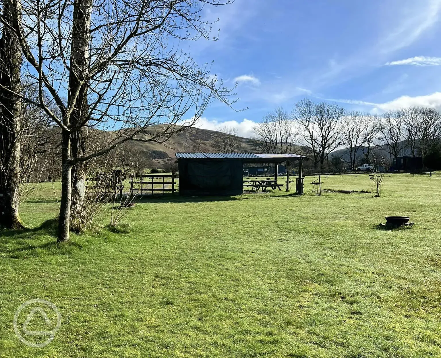 Covered communal area with picnic benches and a fire pit