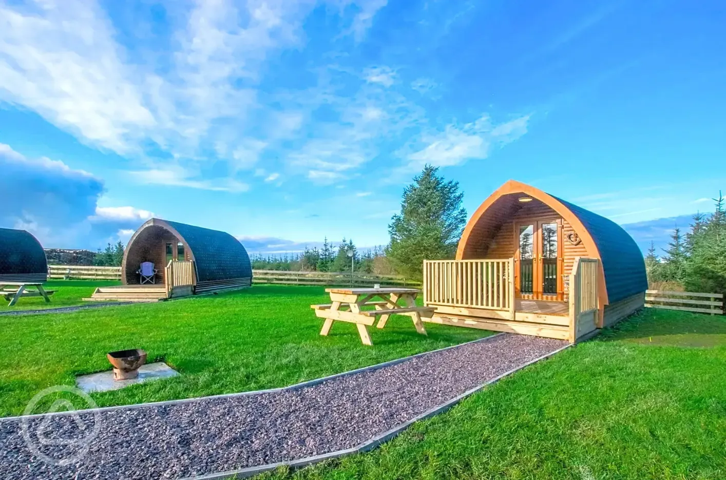 Pods with small decking areas, picnic benches and fire pits
