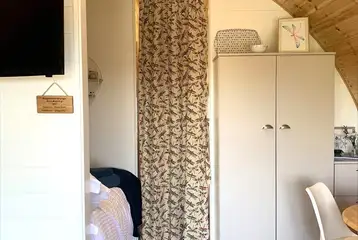 Pod interior with a double bed, dining area, TV and dividing curtain Pod interior with a double bed, dining area, TV and dividing curtain
