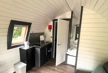 Ensuite glamping pod interior with a double bed, kitchenette, and sofa