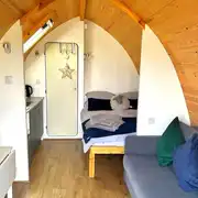 Glamping pod interior with double bed, sofa bed and kitchenette
