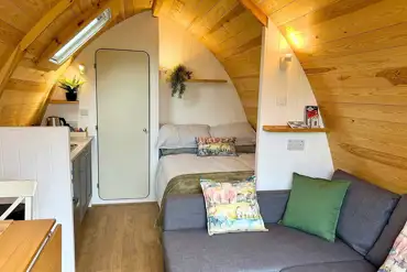 Glamping pod interior with a double bed, double sofa bed and kitchenette