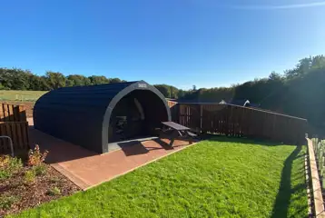 Glamping pod with a patio, grass area and picnic bench