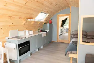 Glamping pod interior with a double bed, double sofa bed and kitchenette