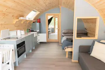 Glamping pod interior with a double bed, double sofa bed and kitchenette
