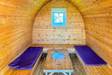 Camping pod (four person) interior with wrap around seating converting into beds Camping pod (four person) interior with wrap around seating converting into beds